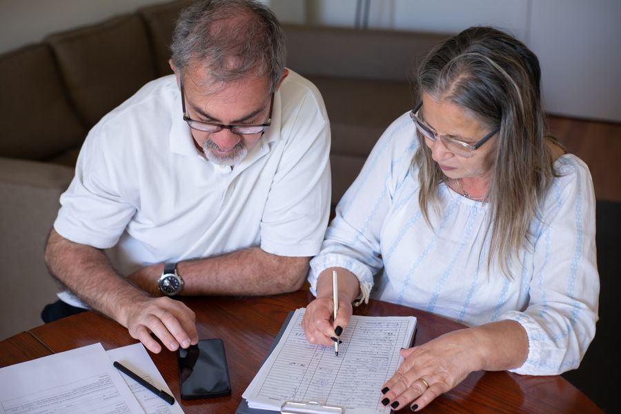 A mature couple organizing paperwork at a table; illustrative stock photograph.