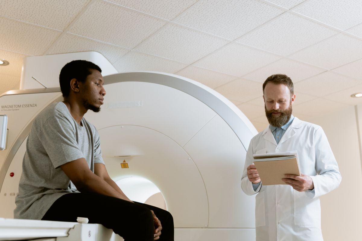 A medical professional reviewing records beside a seated adult and a scanner; illustrative stock photograph.